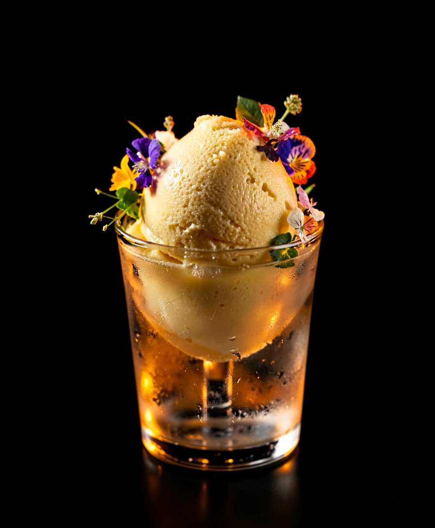 A pale, frozen oyster-cream course dotted with finger lime, side-lit on near-black.